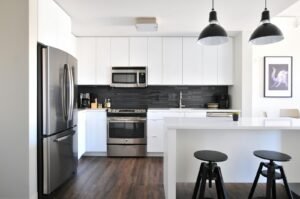 Partner with Now Air Conditioning for professional HVAC maintenance to keep your home in ideal comfort. | A photograph of a modern, clean kitchen with stainless steel appliances, white counters, and black accents.